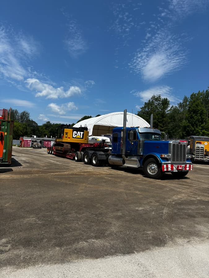 Camion VIAX bleu transportant une pelle CAT